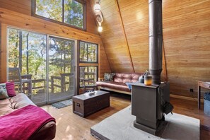 Relax in the living room with stunning forest views through the large windows and stay warm by the wood stove on cooler nights. 