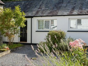 Outside of cottage with gravel path and raised flower beds