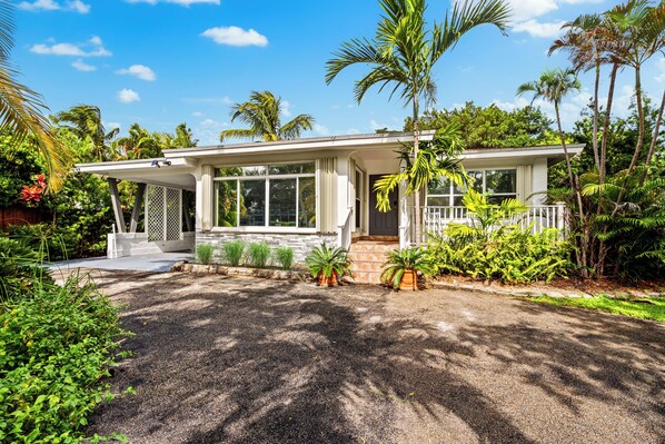 Front view of the home with lush tropical landscaping and large picture windows welcoming in natural light