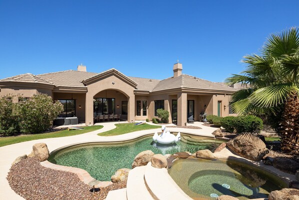 Beautiful Backyard featuring a sparkling pool, hot tub, private patio with outdoor furniture and an outdoor dining table, grill, fire pit, and corn hole set.