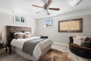 Bedroom1 with queen size bed, oversized chair, dresser, closet, and extra linens