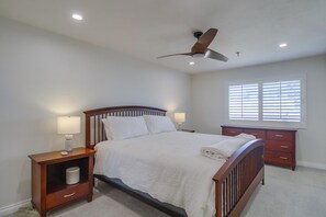 King size bed with dresser, mirrored closets offering additional storage, ceiling fan and in-suite bathroom