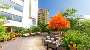 Lush terrace lounge at Hotel Mousai with colorful foliage & seating.