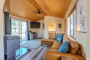 Relax in the cozy living area at Owl’s Nest Cabin, featuring a comfortable leather sectional, wood fired stove,  65" smart tv,  and incredible panoramic views of the valley and mountains.