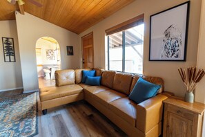 Relax in the cozy living area at Owl’s Nest Cabin, featuring a comfortable leather sectional, nature-inspired artwork, and incredible panoramic views of the valley and mountains.