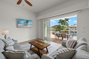 Living room over looking pool/canal. 65 inch wall mounted TV with full sliders