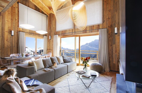 Unwind in this bright and airy living room with cosy seating and large windows offering panoramic views of the stunning alpine landscape.