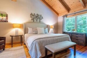 Relax in a vaulted master suite with king bed & views of the tranquil woods