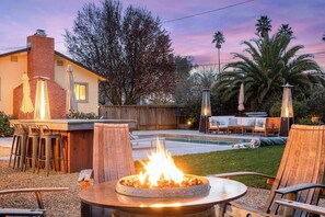 Fire pit with wine barrel chairs for relaxing. Several additional outdoor heaters are appropriately distributed around the large yard. 