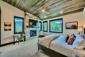 Wake up in this serene bedroom featuring stunning mountain views, a cozy fireplace, and a rustic design, offering the perfect retreat for relaxation and comfort.