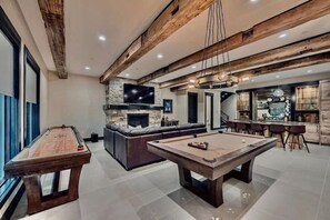 Relax and unwind in this spacious, modern entertainment room featuring a pool table, large TV, and stylish design—perfect for fun-filled nights with family or friends.