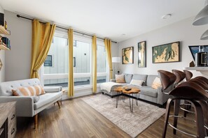 Step into this bright, open-concept living room, where natural light pours in through large windows, creating a warm and inviting atmosphere. The airy layout seamlessly blends the living and dining areas, perfect for relaxing or gathering with loved ones.