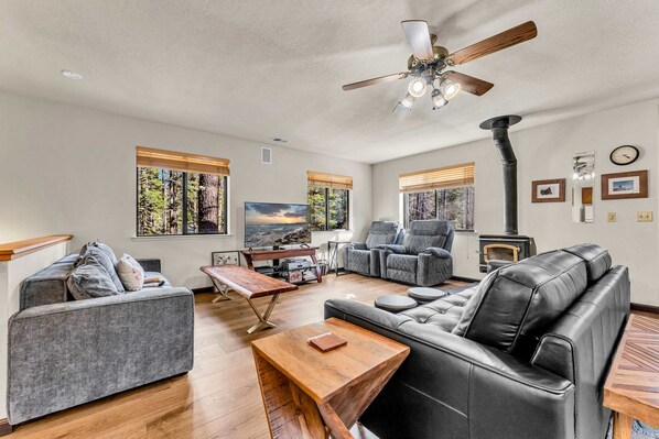Living Room: Open layout, 2 couches, 2 reclining chairs, 50” Smart TV, wood-burning fireplace, ceiling fan
