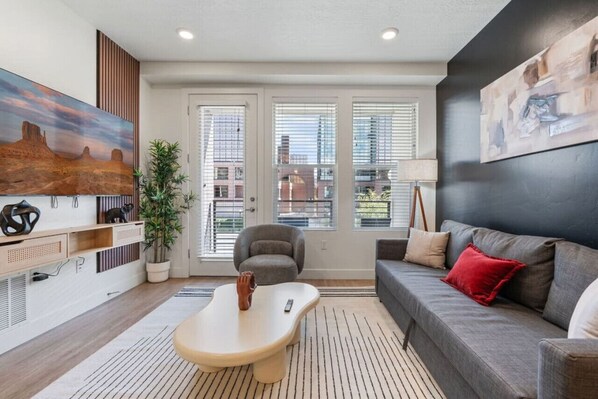 Relax in our airy living room with large windows, comfortable sofas, and a touch of nature from the bamboo plant.