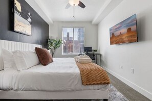 Relax and recharge in this elegant bedroom, featuring a king bed, TV, scenic window, and a touch of greenery.