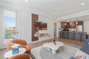 Unwind in our cozy living room, flooded with natural light from floor-to-ceiling windows.