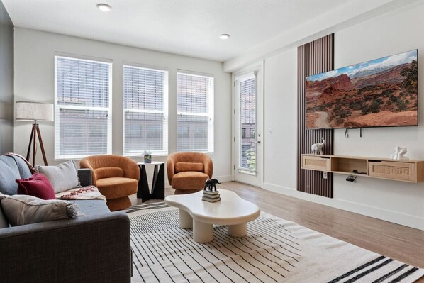 Bright and airy living room with a large TV and stunning views through expansive windows.