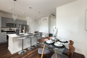 Our dining room offers a serene ambiance with a white orchid centerpiece, large mirror, and stylish seating for four.