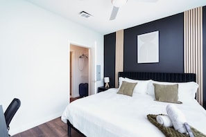 Our bedroom offers ultimate comfort with a king-sized bed, lush plant, and a desk area bathed in natural light.