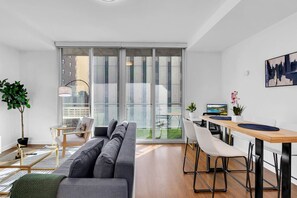 Spacious open-concept living room featuring a cozy couch, TV, workstation, and dining area for ultimate comfort and convenience.
