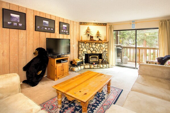 Living room with balcony access, wood burning fireplace and TV