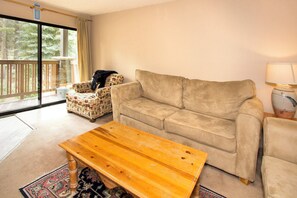 Living room with balcony access, wood burning fireplace and TV