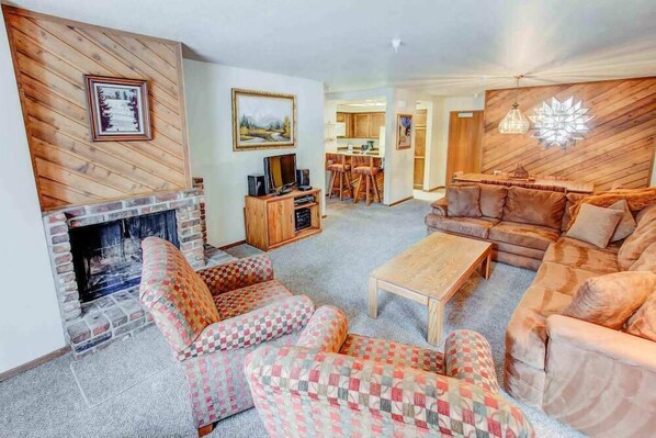 Living room w/ sofa sleeper, wood burning fireplace, and TV