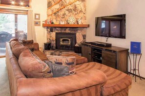Living room w/ DVD player, Youtube TV (and Amazon Firesticks), wood burning fireplace and balcony access w/ BBQ grill