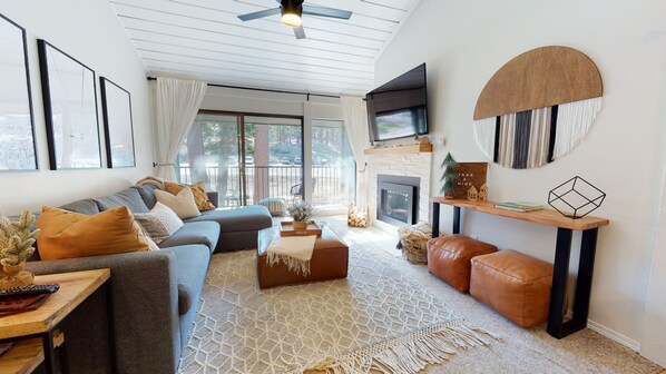 Living room with TV, gas fireplace, balcony access, and sofa sleeper
