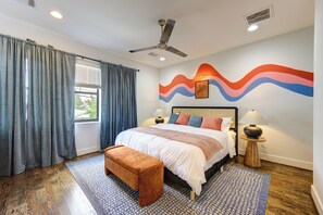 Master bedroom with plush king bed, ceiling fan, and window with curtains