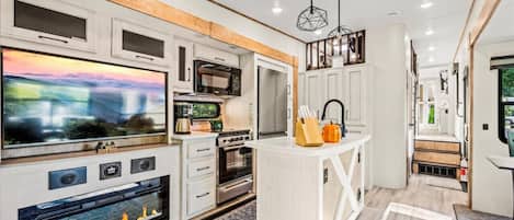 Living area view featuring a large flatscreen TV, Electric Fireplace, and Fully Stocked Kitchen