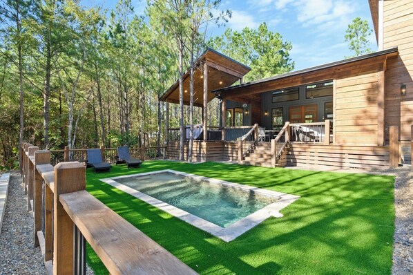 Modern forest cabin with private plunge pool, sun loungers, and spacious deck. Perfect outdoor retreat for relaxation, surrounded by pine trees and natural beauty.
