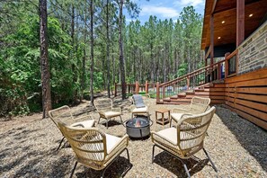 Outdoor fire pit with modern seating nestled in forest surroundings—perfect for evening gatherings and cozy relaxation.