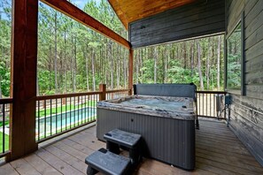 Private cabin hot tub on covered deck with forest view, perfect for a relaxing nature retreat or romantic getaway