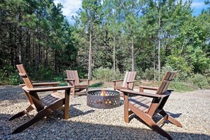 Fire pit with Adirondack chairs nestled in the forest clearing.