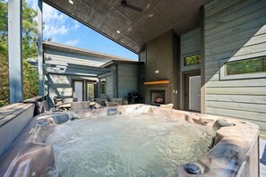 Outdoor hot tub and fireplace lounge on covered cabin deck.
