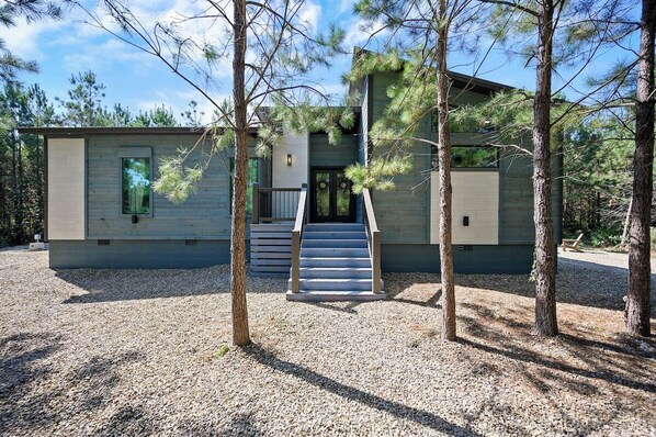 Modern cabin exterior with forest views and front porch entry.