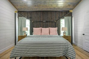 Cozy bedroom with pink pillows and striped bedding, natural wood decor.