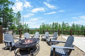 Cozy firepit area with Adirondack chairs and scenic mountain views, perfect for relaxing evenings outdoors.