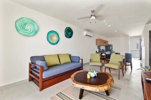 Inviting living room with sofa bed, twin trundle, AC, and ceiling fan.