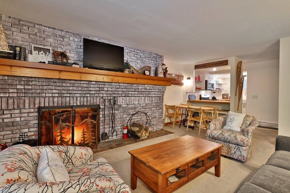 Fireplace, smart TV and stylish sofas in the living room at Sunrise Timberline M1, a charming Killington ski-in, ski-out condo.
