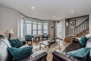 Gather in the cozy family living area featuring large windows that frame expansive views of Georgian Bay. The perfect space to unwind after exploring the Bruce Peninsula, with natural light and serene waterfront vibes.