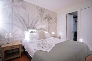 Relax in this cozy bedroom with tropical vibes and plush bedding, perfect for a restful night's sleep.