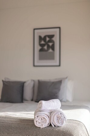 Relax in this serene bedroom with plush pillows and fresh towels, perfect for a restful stay.
