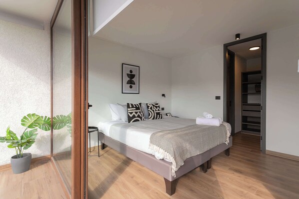 Relax in this serene bedroom with natural light and stylish decor, perfect for a restful stay.