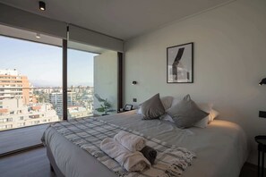 Relax in this chic bedroom with stunning city views, perfect for unwinding after a day exploring Santiago.