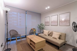 Relax in this cozy living room with modern decor and ample natural light, perfect for unwinding after a day exploring the city.