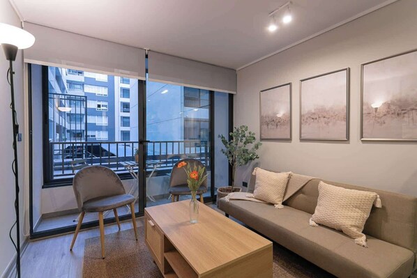 Relax in this cozy living room with a charming balcony view, perfect for unwinding after a day exploring the city.