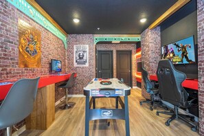 Game on! This fun game room features a classic air hockey table, gaming posters, and a vibrant, modern decor with brick walls - perfect for hanging out and entertainment.