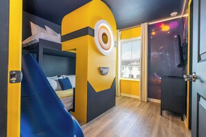 Kids and kids at heart will love this playful bedroom featuring a yellow Minion-inspired decor, fun wall art, a cozy bed, and a mini slide for endless entertainment!